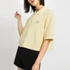 Camiseta polo curta com blocos de cor e logotipo em creme e amarelo
